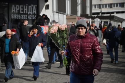 Москва. Мужчина с букетом цветов в преддверии праздника 8 Марта.