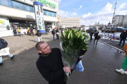 Москва. Мужчина с букетом цветов в преддверии праздника 8 Марта.