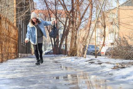 Красноярск. Девушка идет по дороге во время гололеда.