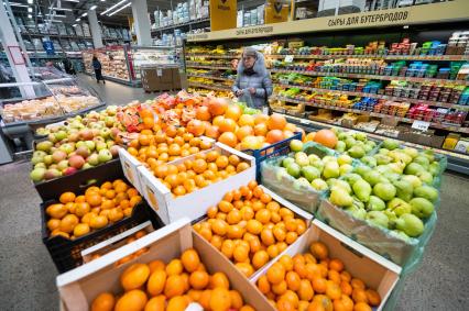 Санкт-Петербург. Женщина выбирает фрукты в супермаркете.