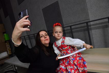Москва. Женщина фотографируется с участницей танцевального ансамбля на выставке ножей`Клинок-традиции и современность`.