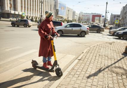 Пермь. Девушка на электросамокате едет по пешеходному переходу.