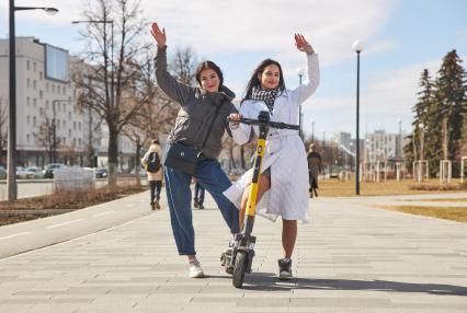 Пермь. Девушки с электросамокатом стоят рядом с  выделенной полосой для самокатов и велосипедов.