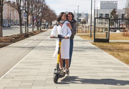 Пермь. Девушки едут на электросамокате рядом с  выделенной полосой для самокатов и велосипедов.