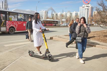 Пермь. Девушка едет на электросамокате по пешеходному переходу.