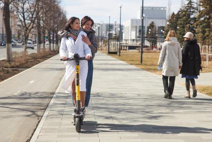 Пермь. Девушки едут на электросамокате рядом с  выделенной полосой для самокатов и велосипедов.