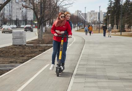 Пермь. Девушки едут на электросамокате по выделенной полосе для самокатов и велосипедов.