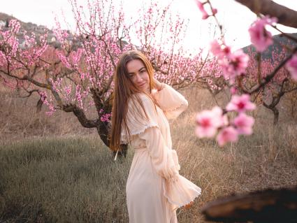 Крым. Девушка позирует на фоне цветущего персикового дерева.