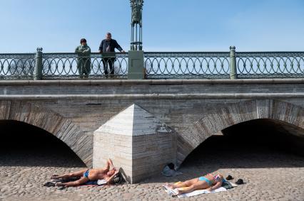 Санкт-Петербург. Люди на мосту смотрит на загорающих у Петропавловской крепости.