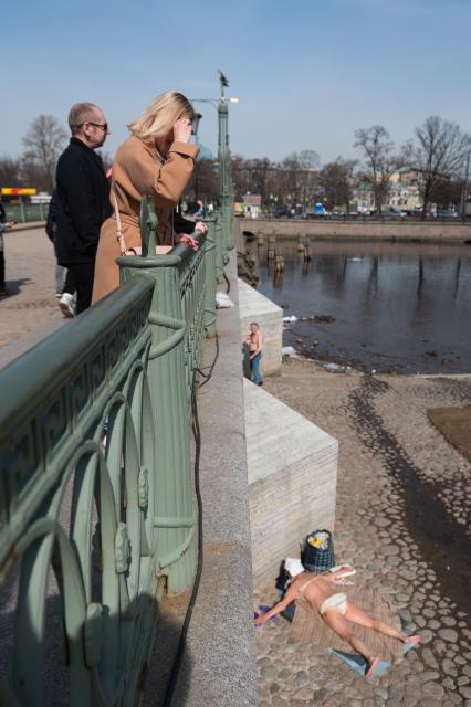 Санкт-Петербург. Женщина на мосту смотрит на загорающих людей у Петропавловской крепости.