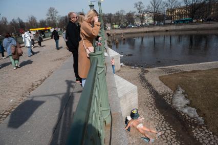 Санкт-Петербург. Женщина на мосту смотрит на загорающих людей у Петропавловской крепости.