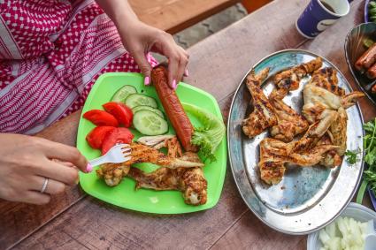 Красноярск. Жареные куриные крылья, сосиска и овощи на тарелке.