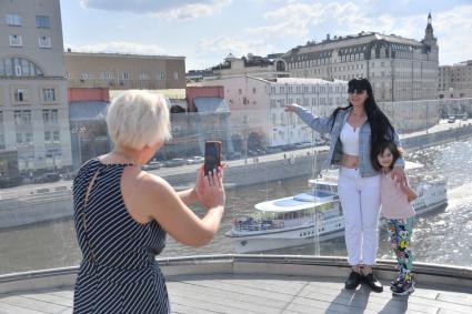 Москва. Женщина с ребенком фотографируются на Парящем мосту в парке `Зарядье`.