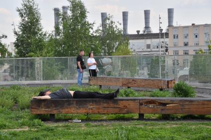 Москва. Мужчина спит на скамейке в парке `Зарядье`.