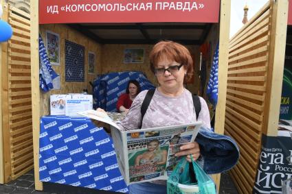 Москва. Женщина читает газету у стенда Издательского дома `Комсомольская правда` на IX ежегодном книжном фестивале `Красная площадь`.