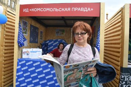 Москва. Женщина читает газету у стенда Издательского дома `Комсомольская правда` на IX ежегодном книжном фестивале `Красная площадь`.