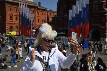 Москва. Женщина фотографирует на Манежной площади  в День празднования Дня России.