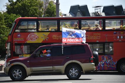 Москва.  Машина с флагом России на улице города.