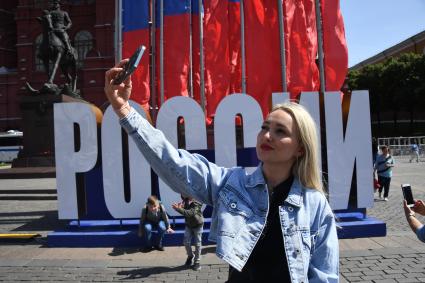 Москва. Женщина фотографирует на Манежной площади  в День празднования Дня России.