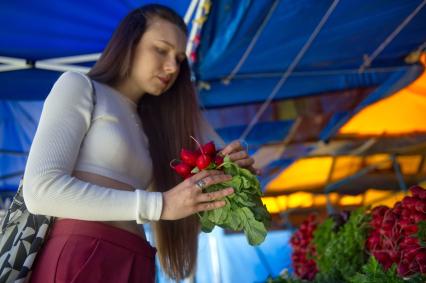 Екатеринбург. Девушка покупает фрукты, овощи и зелень на рынке. Редис