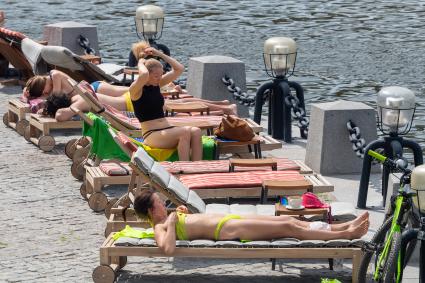 Москва. Горожане загорают на набережной.