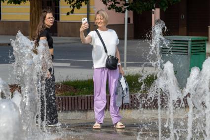Москва. Женщина фотографируется  у фонтана.