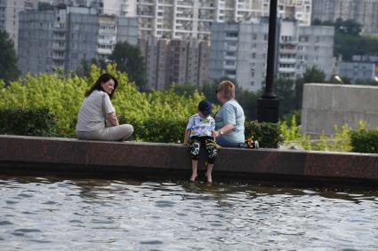 Москва.  Женщины с ребенком сидяту фонтана на Поклонной горе.