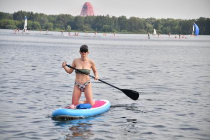 Москва. Девушка плывет на sup-борде у пляжа в Строгино.