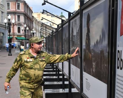 Москва. Мужчина в камуфляже у стендов с фотографиями выставки лауреатов Всероссийского конкурса военной журналистики, которая открылась на Арбате.