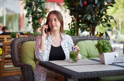 Пермь. Девушка сидит в кафе и разговаривает по мобильному телефону.
