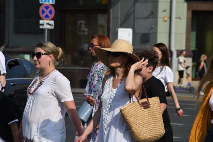 Москва. Женщина в шляпе и в солнцезащитных очках идет по улице.