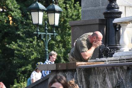 Москва. Мужчина умывается водой из фонтана на Манежной площади.
