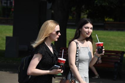 Москва. Девушки с напитками в пластиковых стаканчиках идут по улице.