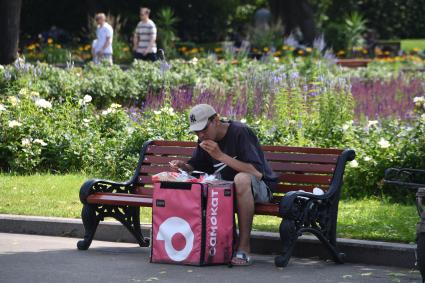 Москва. Курьер `Самоката` обедает в Парке Горького.