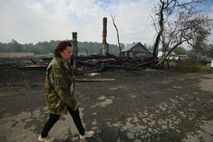 Свердловская область. Женщина идет мимо сгоревшего дома в селе Шайдуриха, в котором огнем было уничтожено 40 построек и погиб 1 человек