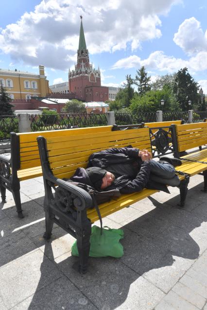 Москва.   Мужчина спит на скамейке на  Манежной площади.