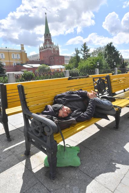 Москва.   Мужчина спит на скамейке на  Манежной площади.
