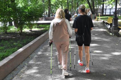 Москва. Женщины с палками для скандинавской ходьбы на бульваре.