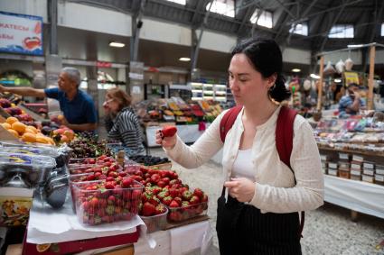 Санкт-Петербург. Девушка выбирает клубнику на Кузнечном рынке.