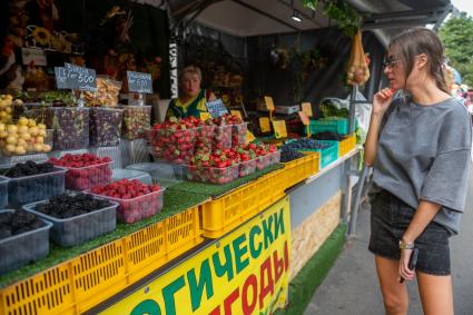 Санкт-Петербург. Девушка выбирает ягоды на Сенном рынке.