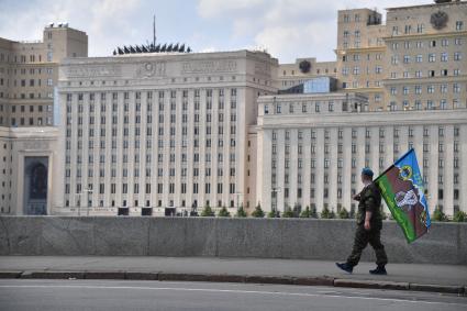 Москва. Десантник с флагом идет по Пушкинской набережной и смотрит на министерство обороны РФ в День Воздушно-десантных войск России.