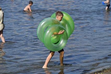 Москва. Мальчик несет надувные круги на пляже озера Белое в районе Косино-Ухтомское.