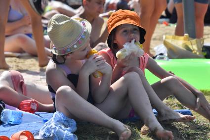 Москва. Девочки едят горячую кукурузу на пляже озера Белое в районе Косино-Ухтомское.