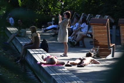 Москва.   Горожане в жаркий день загорают у фонтана.
