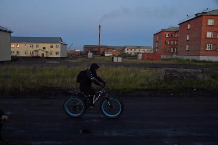 Красноярский край. Хатанга.   Мужчина на велосипеде на улице  поселка.