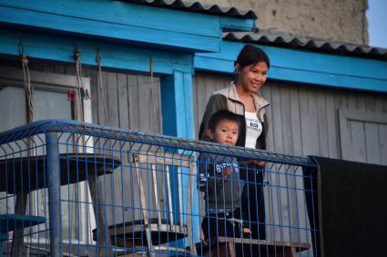 Красноярский край. Хатанга.  Женщина с ребенком  на балконе дома.