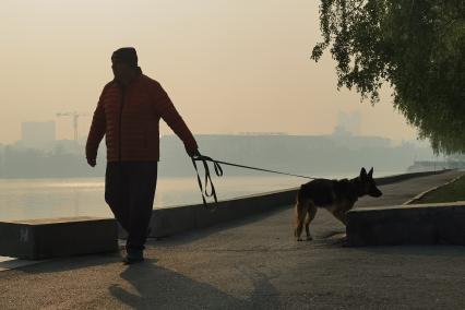 Екатеринбург. Мужчина с собакой на набережной реки Исеть во время смога из-за лесных пожаров