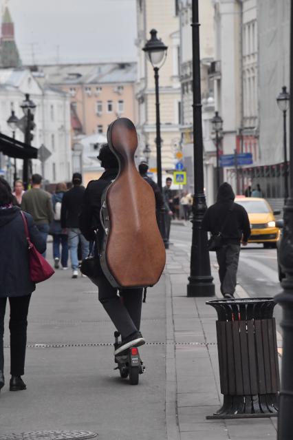 Москва.  Молодой человек едет на самокате.