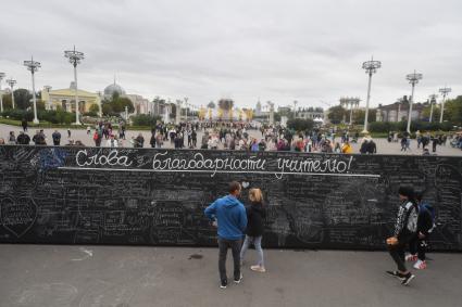 Москва.   Празднование Дня города Москвы на ВДНХ.  Молодые люди у  доски `Слов благодарности учителю`.