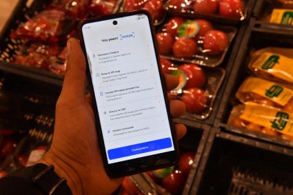 Москва. Мужчина в магазине держит в руках смартфон и с помощью приложения `Госкан` сканирует товары.